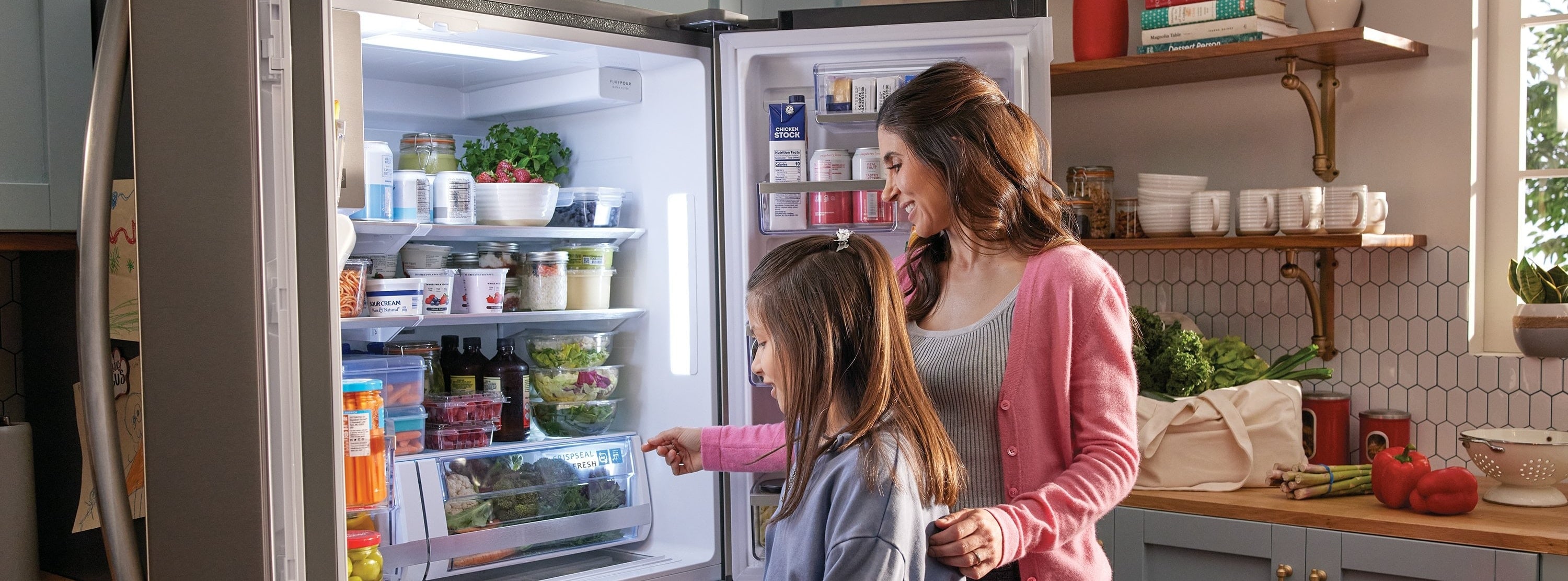 Mom and daughter opening a french door refrigerator