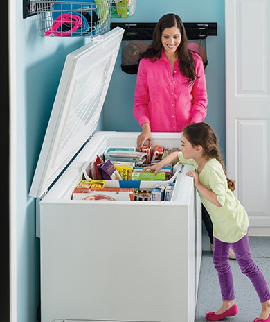 chest freezer in a garage with people reaching in