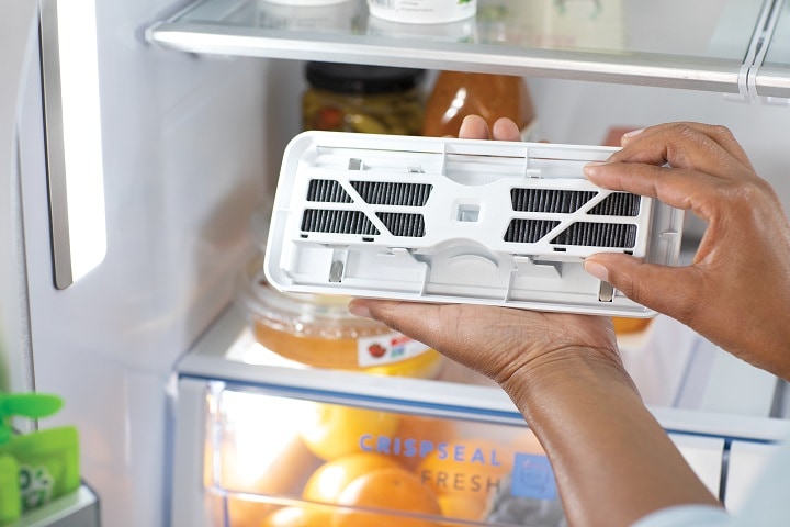 showing the process of changing an air filter in a refrigerator to keep odors at bay and produce fresher longer