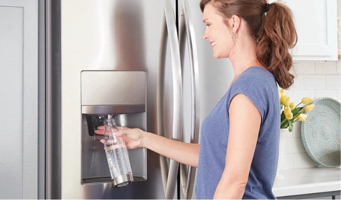 Lady pouring water into a glass from the refrigerator