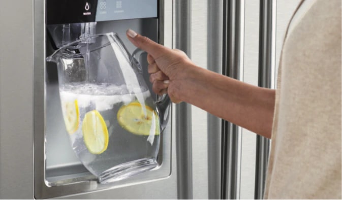 Water pitcher filled with water and lemons from a refrigerator