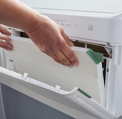 picture of someone installing a room air filter into their window air conditioner